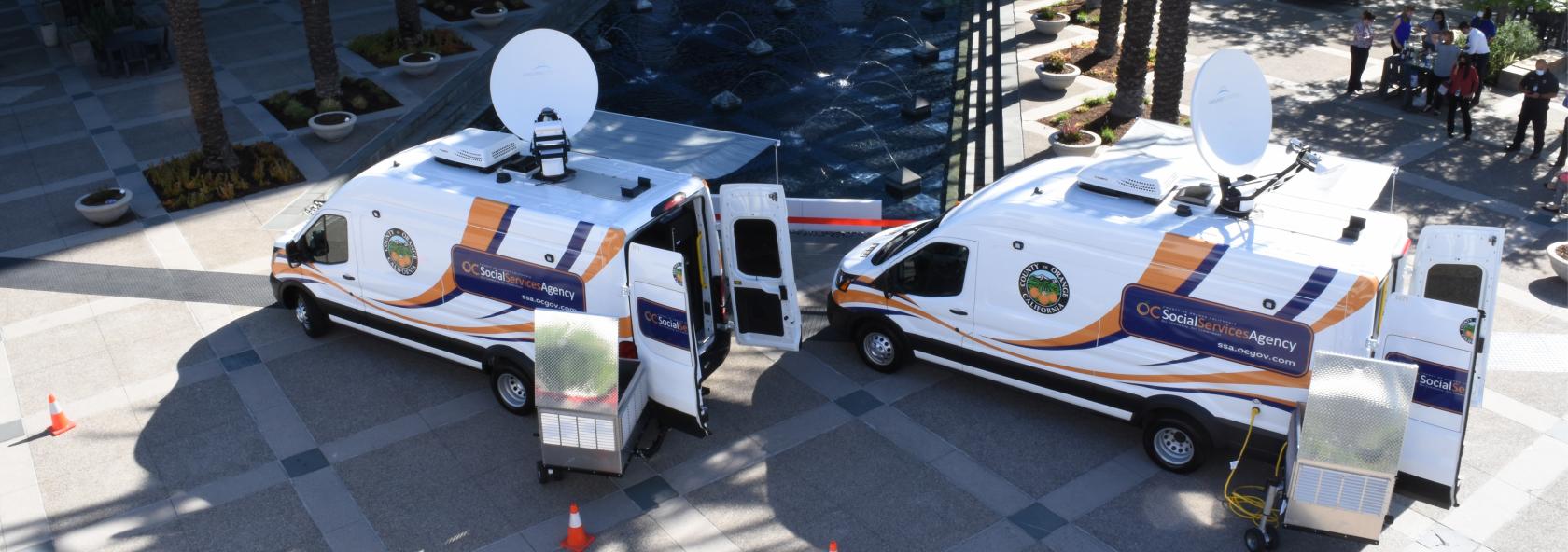 Two vans parked at an event labeled OC Social Services Agency