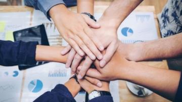 Eight hands together about to cheer. 