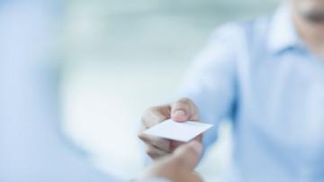 A man hands a card to another person.