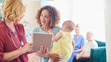 A medical professional talks to a woman holding a baby.