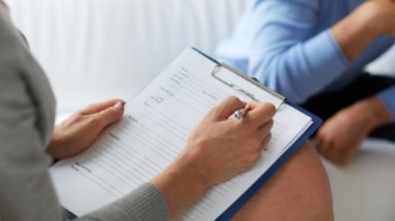 A woman taking down information on a form while a man talks