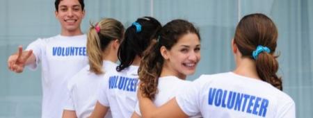 A group of young adults wearing shirts with VOLUNTEER written on the back